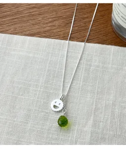 Inquadratura dettagliata della collana in argento S925 con smiley e goccia verde