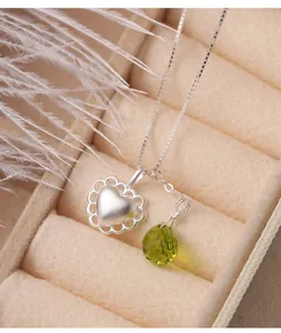 Close-up of S925 silver necklace with matte heart pendant and green waterdrop charm.