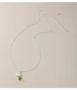 Close-up of s925 silver necklace featuring an apple pendant and a green water drop gem