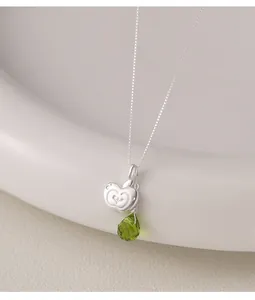 Detail view of S925 silver necklace featuring apple pendant and faceted green teardrop charm