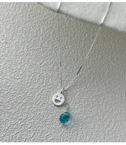 Dettaglio ravvicinato della collana in argento s925 con smiley e cristallo blu a goccia