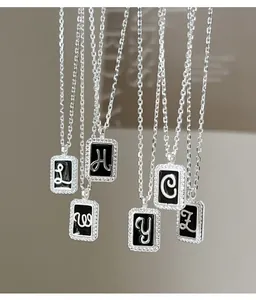 Close-up of S925 silver necklaces with black enamel letter pendants and diamonds