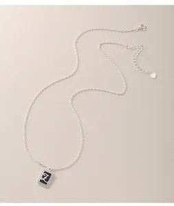 Close-up of S925 silver necklace with rectangular letter E pendant and heart charm.