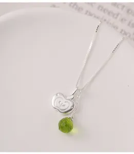Detailed macro shot of an irregular S925 silver apple pendant with a green gemstone drop