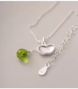 Detailed view of S925 silver necklace with apple pendant and green crystal drop