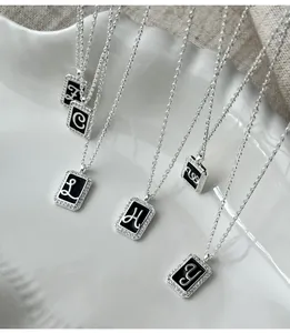 Macro detail of S925 silver necklaces with black enamel letter charms and crystal inlay
