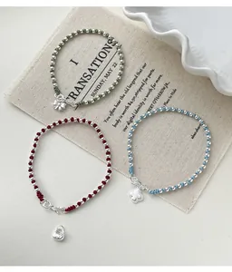Detailed view of s925 silver bow and clover charms on colorful woven rope bracelets