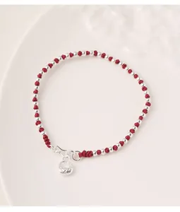 Detailed view of S925 silver beads and red woven cord bracelet in minimalist style