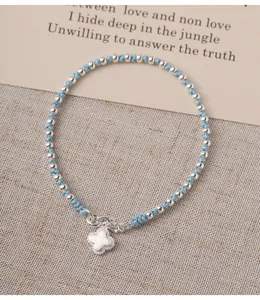 Close-up detail of S925 silver beaded bracelet with blue cord and four-leaf clover charm