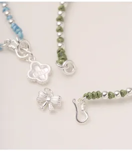 Macro detail showing S925 silver bow and clover charms with colorful braided rope texture