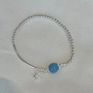 Detailed view of S925 silver beaded elastic bracelet with blue stone and starfish charm