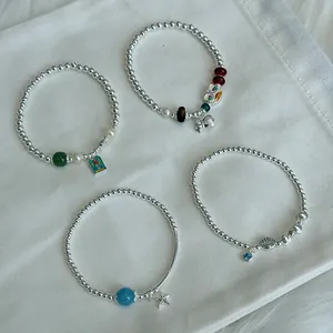 Detailed view of four S925 silver beaded bracelets with starfish and shell charms