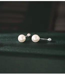 Close-up of 925 sterling silver faux pearl screw back earrings on green fabric