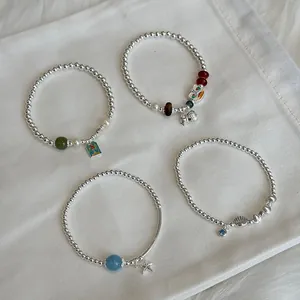 Detailed view of four S925 silver beaded elastic bracelets with various unique charms