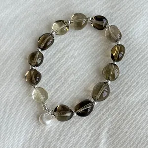 Detalle de pulsera de plata S925 hecha a mano con cuentas de cristal ahumado y dije de corazón
