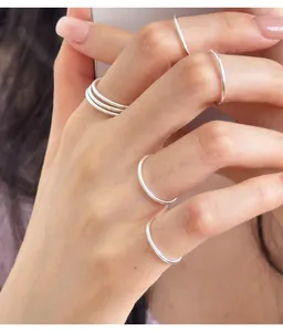 Detail of minimalist 999 sterling silver rings worn on fingers for an elegant stacked look