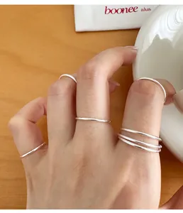 Close-up of 999 sterling silver minimalist plain band rings worn on multiple fingers