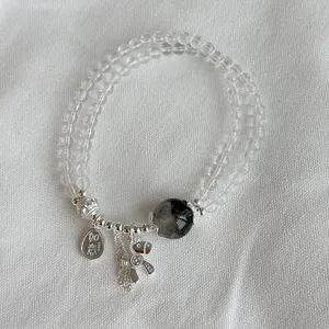 Detalle de la pulsera de cristal natural de plata S925 con dije de perro globo tierno.