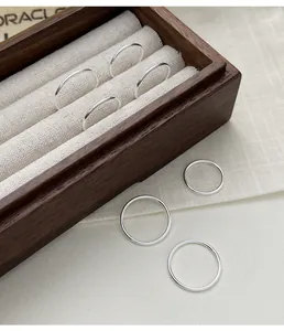 Detailed macro shot of minimalist 999 sterling silver plain band rings in a wooden box.
