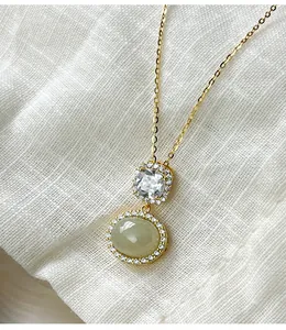 Close-up of elegant gold plated S925 silver necklace with oval jade and sparkling crystals.