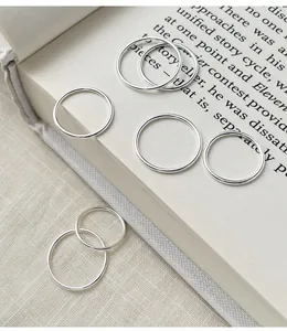 Detailed macro shot of multiple minimalist silver plain rings scattered on an open book