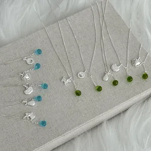 Detail shot of silver necklaces with various charms and colorful glass crystal drops