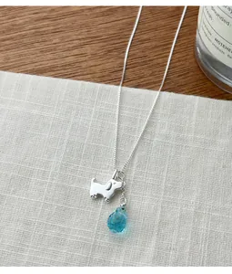 Macro detail view of a silver cute dog pendant necklace with blue waterdrop crystal.