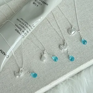 Macro detail of S925 silver necklaces with cute charms and blue crystal pendants