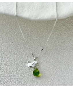 Close-up of S925 silver dog necklace featuring a green teardrop-shaped gemstone.