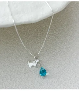 Macro view showing the silver cute dog charm and faceted blue teardrop pendant