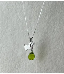 Detail view of an S925 silver necklace featuring a cute dog pendant and green gem.