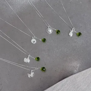 Close-up detail of S925 sterling silver necklaces featuring cute charms and green crystal drops