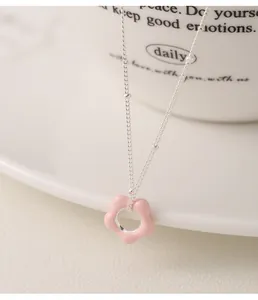 Detail of a pink enamel flower pendant on a 925 sterling silver chain necklace.