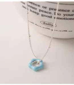 Detailed macro view of minimalist 925 sterling silver necklace with blue enamel flower pendant