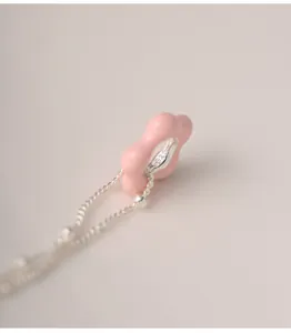 Detailed macro view of a pink enamel flower pendant on a 925 sterling silver chain