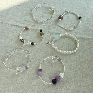 Primer plano de elegantes pulseras de plata 925 con cristales de colores y perlas
