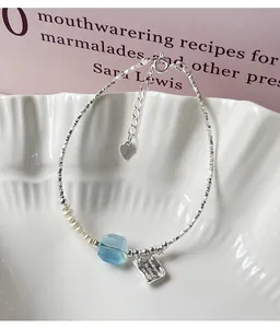 Macro view of a 925 silver bracelet with pearls, aquamarine, and an engraved charm.