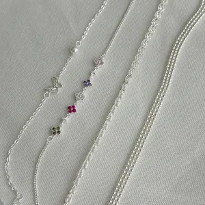 Close-up of S925 silver chain bracelets featuring butterfly and floral charms