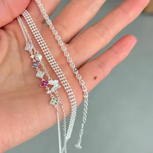 Close-up of S925 silver bracelet set featuring butterfly and flower charms on a hand