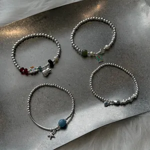 Detail view of four S925 silver beaded bracelets with unique charms on a metal tray.