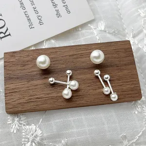 Elegant 925 sterling silver pearl screw-back earrings set on a wooden display.