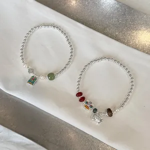 Close-up detail of S925 sterling silver beaded stretch bracelets with jade and pearl charms.