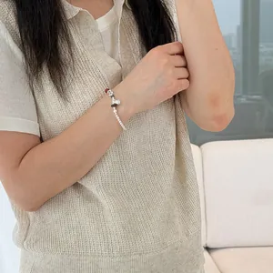 Detail of a minimalist S925 silver bead elastic bracelet worn on a woman's wrist