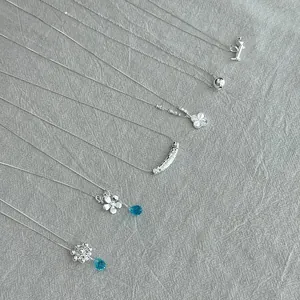 Detail shot of various 925 sterling silver minimalist necklaces on grey linen