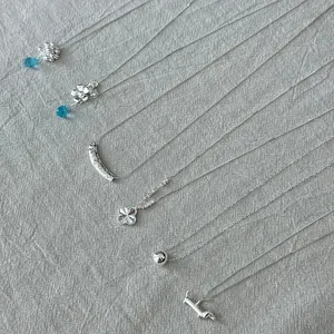 Collection of various 925 sterling silver minimalist necklaces on gray linen fabric