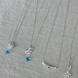 Collection of four 925 sterling silver necklaces on textured grey fabric background.