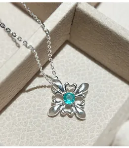 Primo piano di una collana a fiore di iris in argento 925 con una gemma verde vivace.