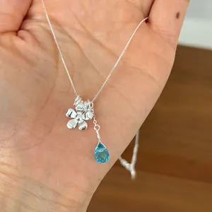 Detailed shot of 925 sterling silver necklace with flower and blue teardrop pendant