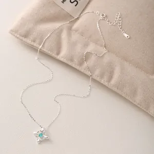 Collana iris in argento S925 con zircone blu su uno sfondo di morbido tessuto beige.