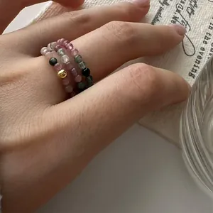 Close-up of handmade tourmaline beaded elastic rings with a gold accent bead